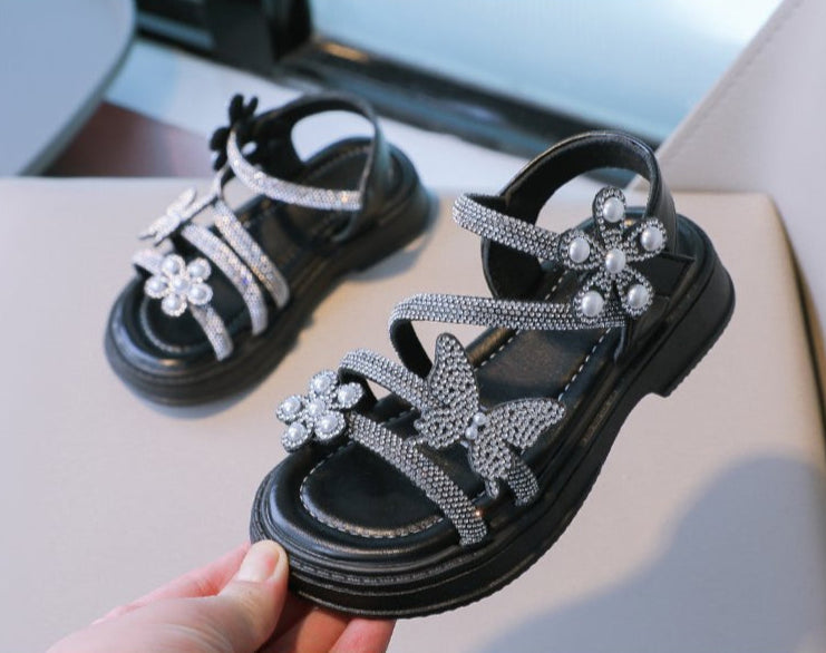 Sandalias infantiles con mariposas brillantes.
